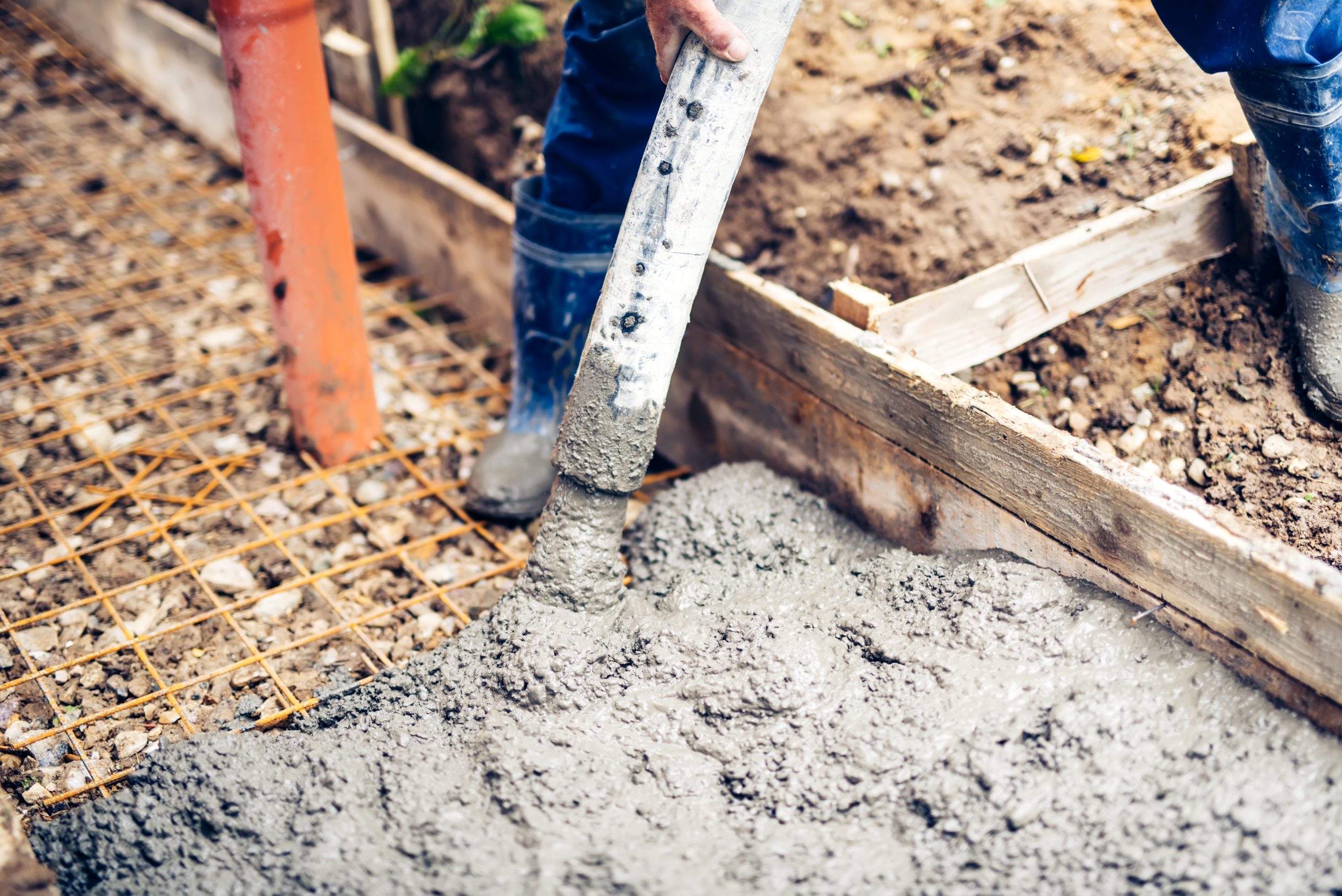 Construction worker pouring cement and concrete over steel beams