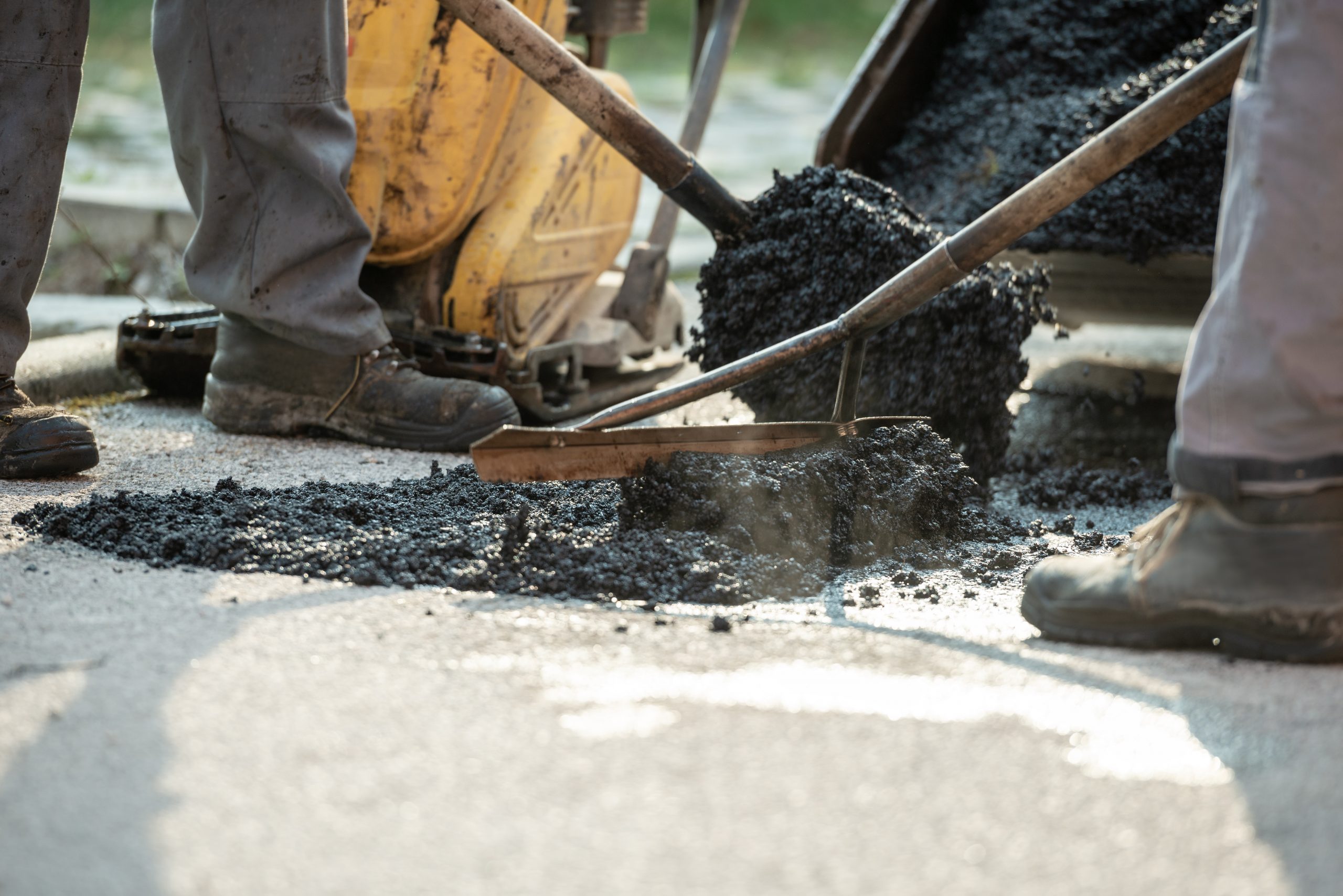 Construction workers performing patchwork on the road